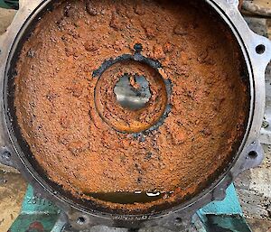 A large, round metal lid is caked with a brwn substance