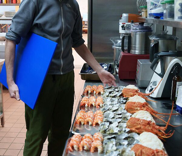 An expeditioner surveys the array of seafood being plated up in the kitchen.