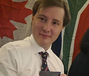 An expeditioner at the dinner table holding an unknown book.