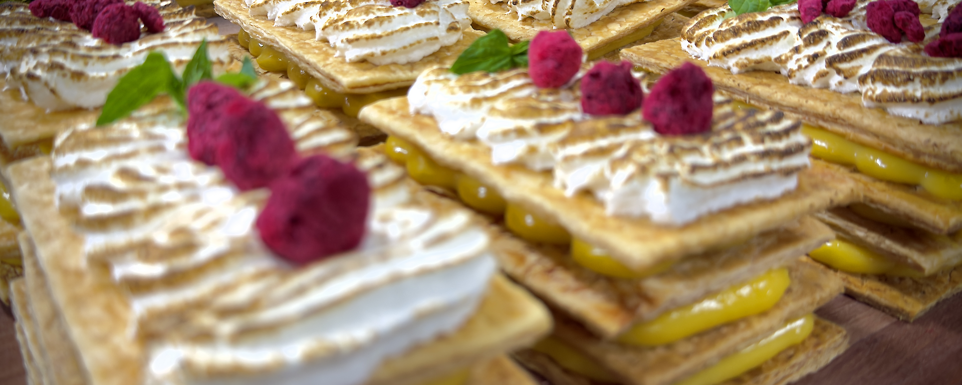 Picture of multi-layered desserts with colourful dried raspberries and mint on top.