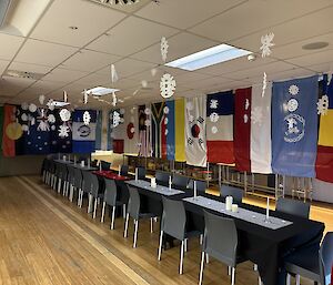 A long table, adorned with candles is surrounded by the flags of many countries represented in Antarctica