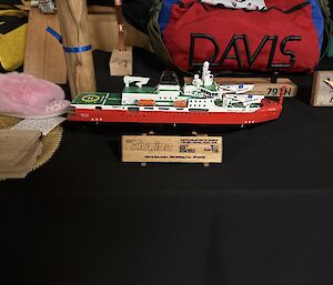 A small wooden replica of a red and white ship, called the Nuyina, is displayed on a table.