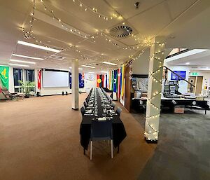A long dining table set up for a midwinter feast. White fairy lights are wrapped around poles and strung from the ceiling.