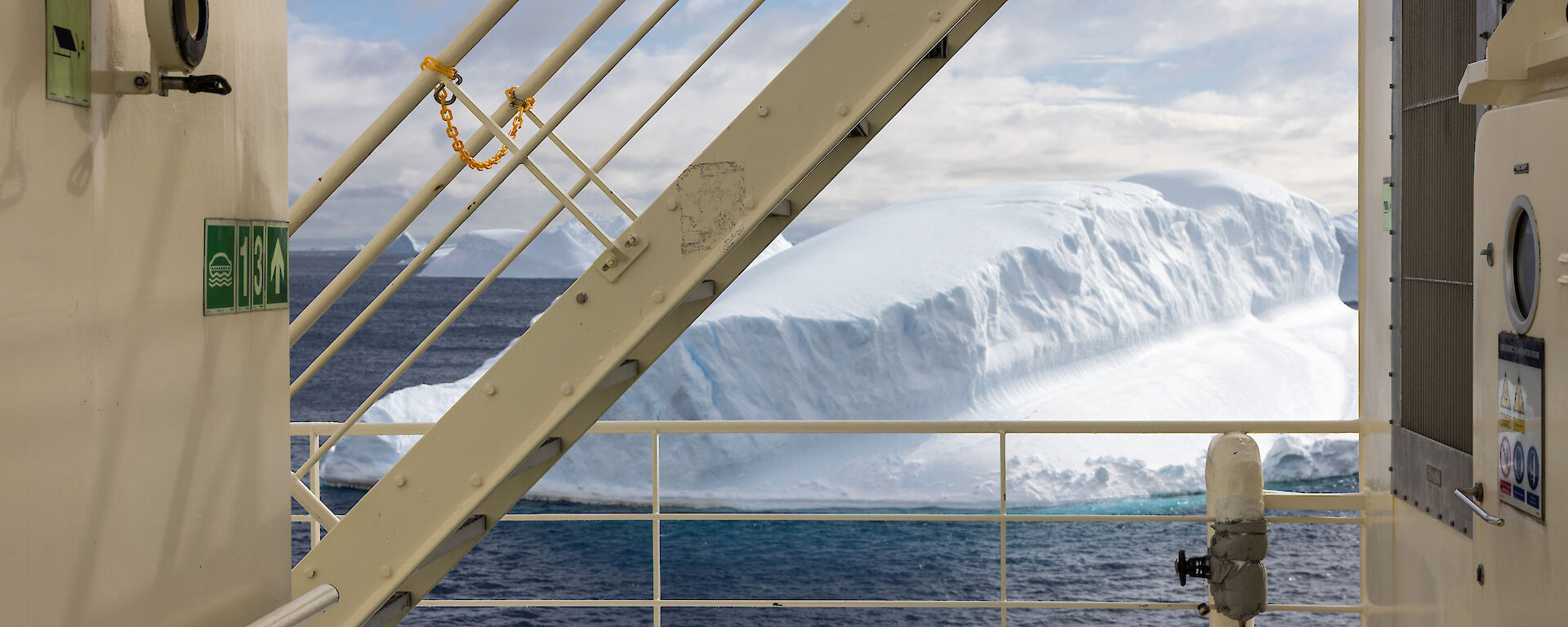 A picture of the deck of the Nuyina, with icebergs floating in the sea in the background.