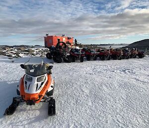 A skidoo and quad bikes lined up in the snow.