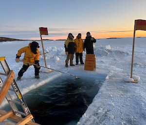 An expeditioner maintaining the swimming hole cut into the sea ice, before the surface starts to freeze back up again