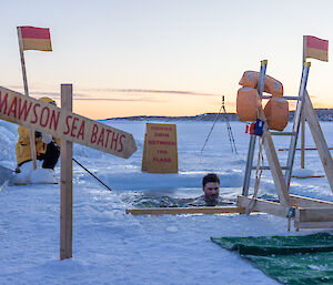An expeditioner seemingly relaxed and calm, treading water in the sea ice hole