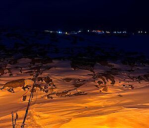 A fuel line running over the snow, lit by artificial light, with the station lights in the background