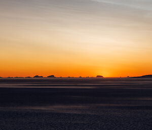 A photo of the sunrise over the sea ice and icebergs that are locked in position
