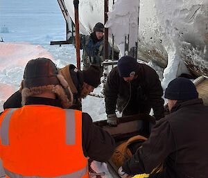 A group in hi vis kneel in the snow around a fuel pump