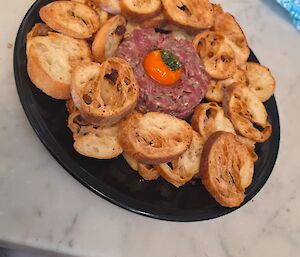 Raw looking mince with bits of toast around the plate