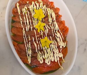 smoked salmon in a white bowl on a bench