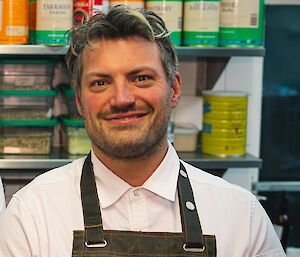 A smiling man in a white shirt and apron