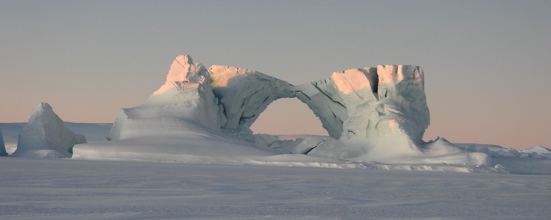 An ice arch formed on the sea ice, with clear skies in the background