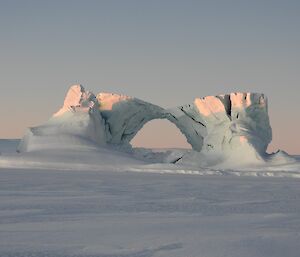 An ice arch formed on the sea ice, with clear skies in the background