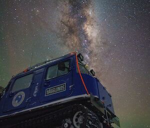 A picture of a blue Hagglands vehicle taken at night, with an amazing lit-up milky way and stars overhead