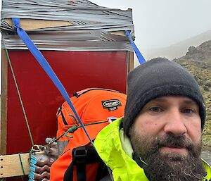 An expeditioner at Macquarie Island, wearing a pack that has a large solar panel mounted on it.