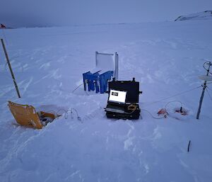 A bright laptop screen is visible in a black box next to a range of science equipment sitting on sea ice