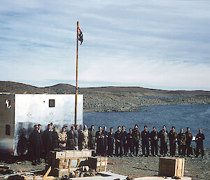A group of people standing next to a flagpole flying the Australian National Flag and a partially built building