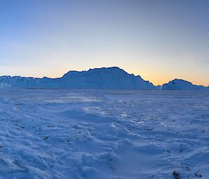 A panorama photo of Auster Rookery in the distance, surrounded by sea ice and jagged ice bergs