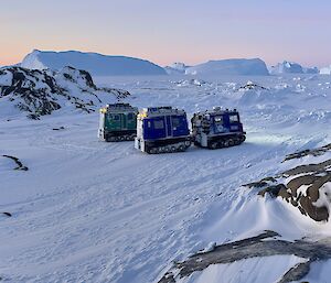 Two Haggs parked on the sea ice, surrounded by rocky island features and an orange field hut to the left