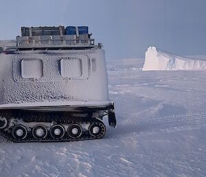 A Hagglands vehicle on the sea ice early morning, overlooking ice cliffs in the background with a bright moon above