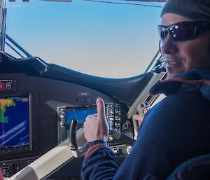 A man in the pilot's seat of a small plane, looking back to the camera