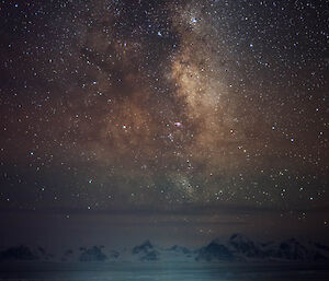 The milky way and stars at night over a brightly lit station