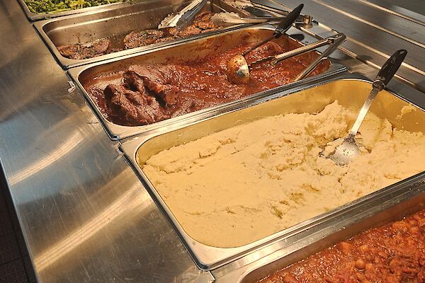 A stainless steel bain marie with vegetables, meat and mashed potato