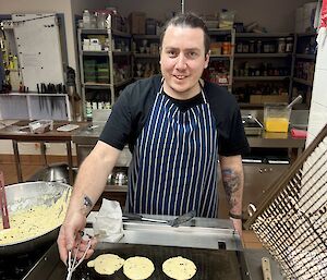 An expeditioner cooking chocolate-button pancakes in the kitchen