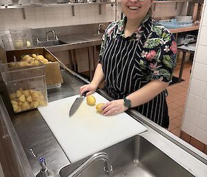 An expeditioner in the kitchen, chopping potatoes on a cutting board
