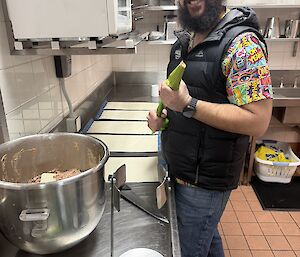 An expeditioner leaning over a kitchen bench, piping sausage rolls