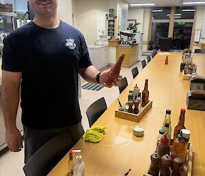 An expeditioner at the messing table, topping up condiment and sauce bottles