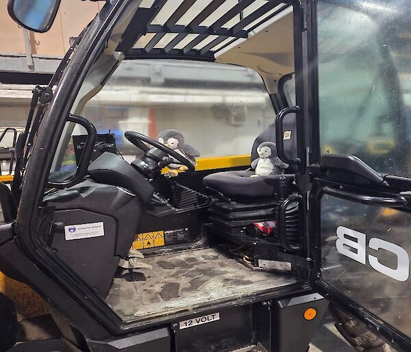 A toy penguin sitting in an all-terrain vehicle