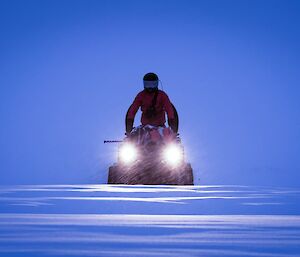 Deep blue sky with a person on a quad bike with its lights on