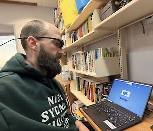 An expeditioner doing a cognitive test on a laptop, while wearing a set of special glasses that monitor eye movements and reactions