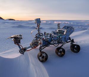 A fully constructed Mars Rover model on a snowy embankment, with sea ice vista in background