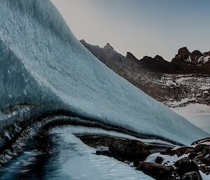 A picture of a wind scour 'cliff' amongst a jagged mountain backdrop