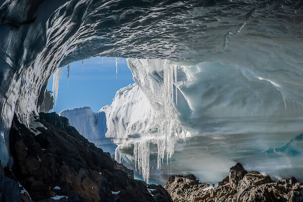 An ice cave with icicles dripping from the roof and a wave-like ceiling