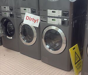 A washing machine with a sign saying 'dirty'