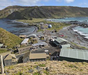 A cluster of khaki and brown buildings on a narrow isthmus with a plateau in the background