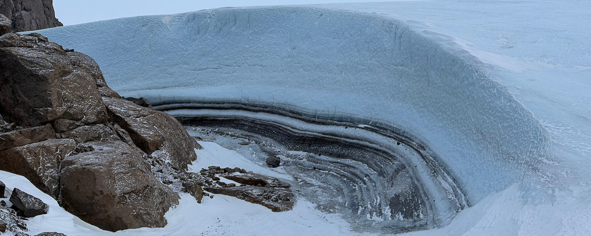A build-up of ice that has created a layered wall around a large rock feature