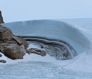 A build-up of ice that has created a layered wall around a large rock feature