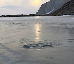 Very smooth and slippery ice covering teh ground with mountain features in background