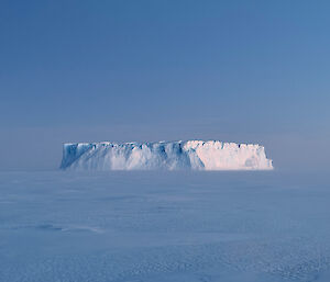 A large and impressive ice berg surrounded by sea ice