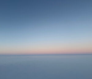 A seemingly endless photo of featureless sea ice, with early morning colours in a cloudless sky
