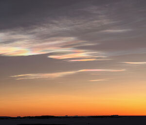 An early sunset over the sea ice, with 'mother of pearl' clouds in the sky that resemble oil slicks