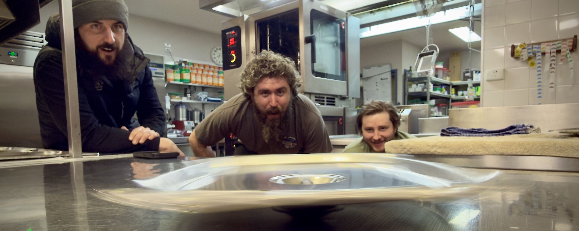 a spinning Bain-marie lid on a kitchen top bench, with expeditioners looking on