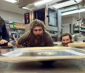a spinning Bain-marie lid on a kitchen top bench, with expeditioners looking on