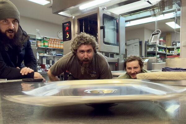 a spinning Bain-marie lid on a kitchen top bench, with expeditioners looking on
